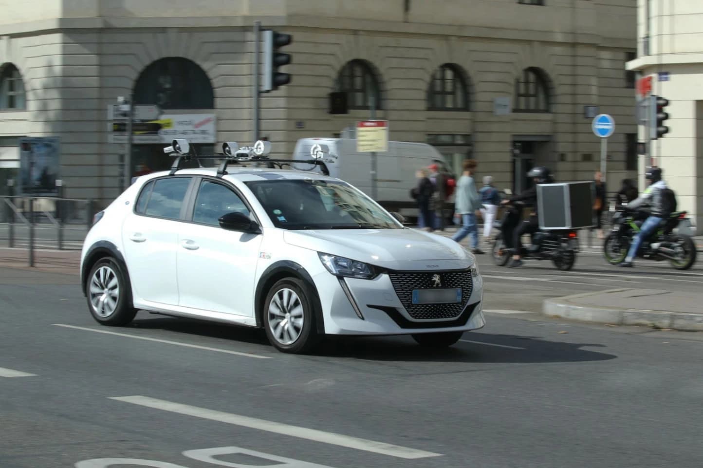 Voiture LAPI municipale équipée de caméras latérales scannant des plaques d'immatriculation sur une rue urbaine pavée, avec des véhicules garés de part et d'autre