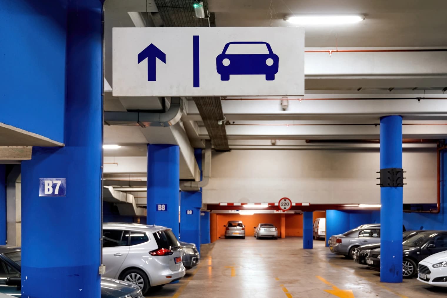 Vue intérieure d'un parking souterrain avec rampe d'accès et barrière automatique
