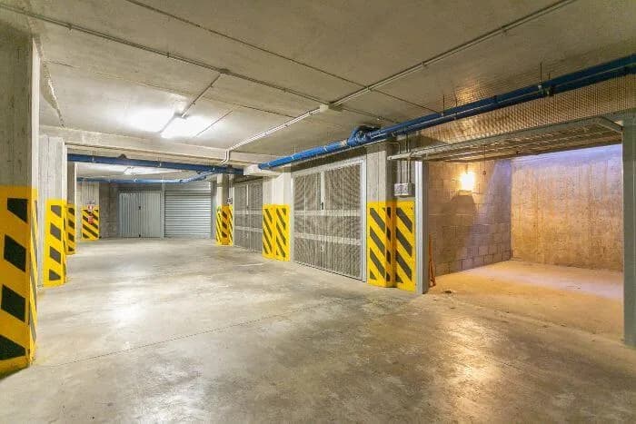 Vue d'un parking souterrain parisien montrant côte à côte une place couverte ouverte et un box fermé avec porte individuelle