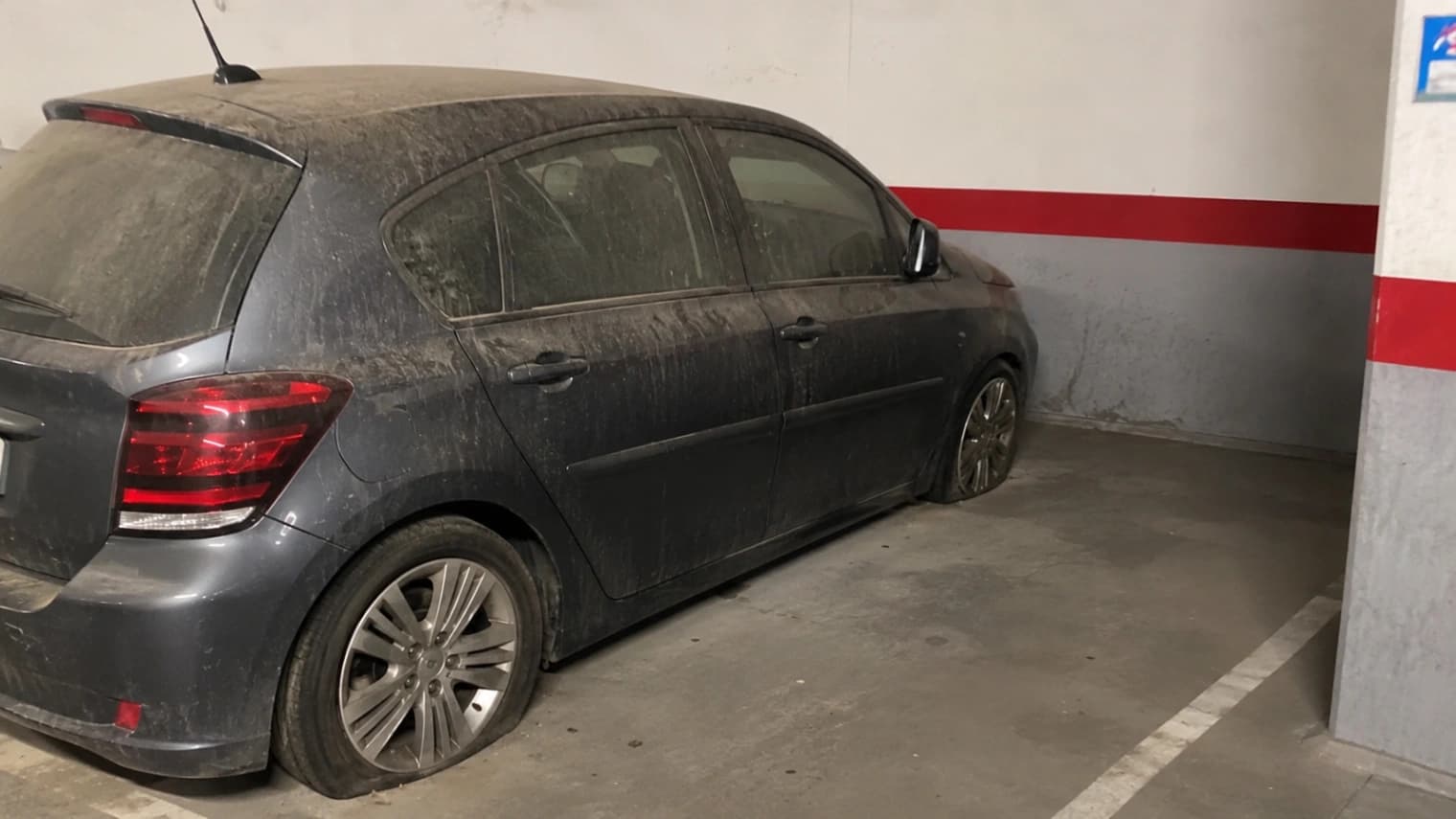 Véhicule abandonné immobilisé sur une place de parking privée dans une copropriété, en attente de procédure d'enlèvement